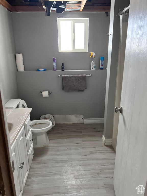 Bathroom featuring wood finished floors, toilet, vanity, and baseboards