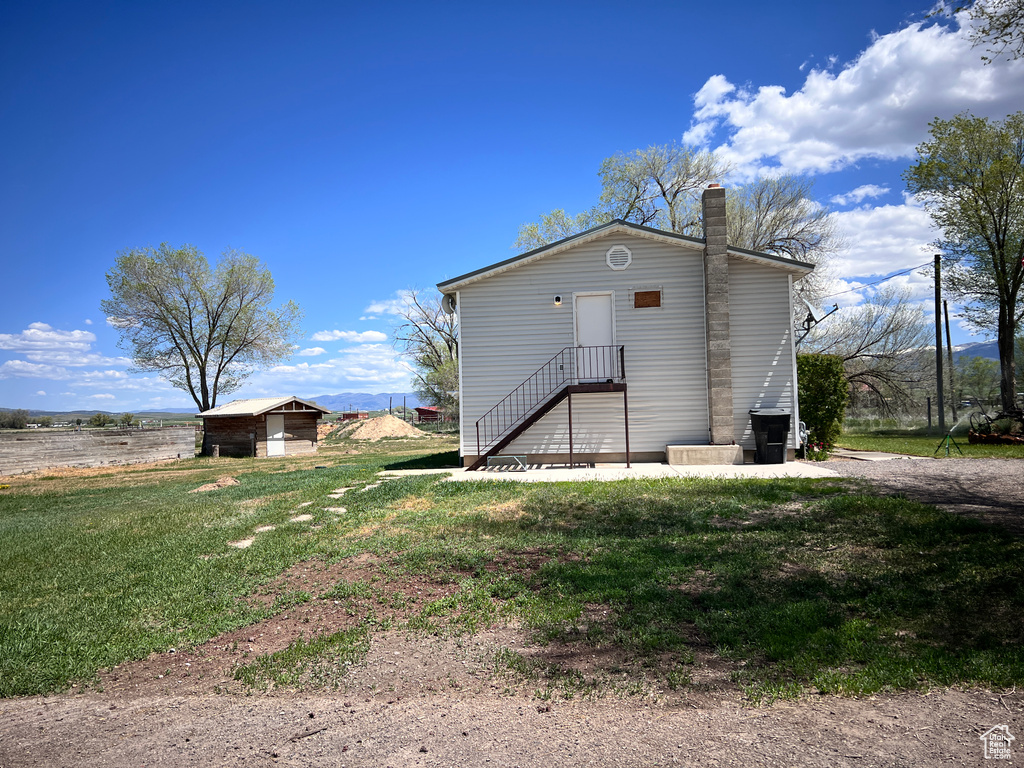 Rear view of house featuring a chimney and a yard