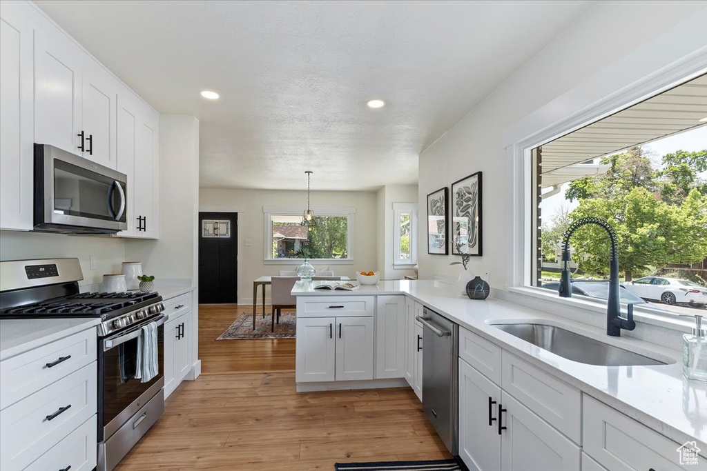 Kitchen featuring appliances with stainless steel finishes, a sink, light countertops, recessed lighting, and light wood-style flooring