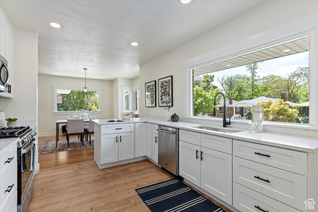 Kitchen with stainless steel appliances, a sink, light countertops, white cabinetry, and recessed lighting