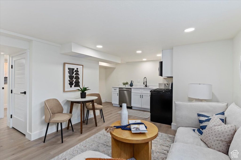 Living area with light wood-type flooring, recessed lighting, baseboards, and bar with sink