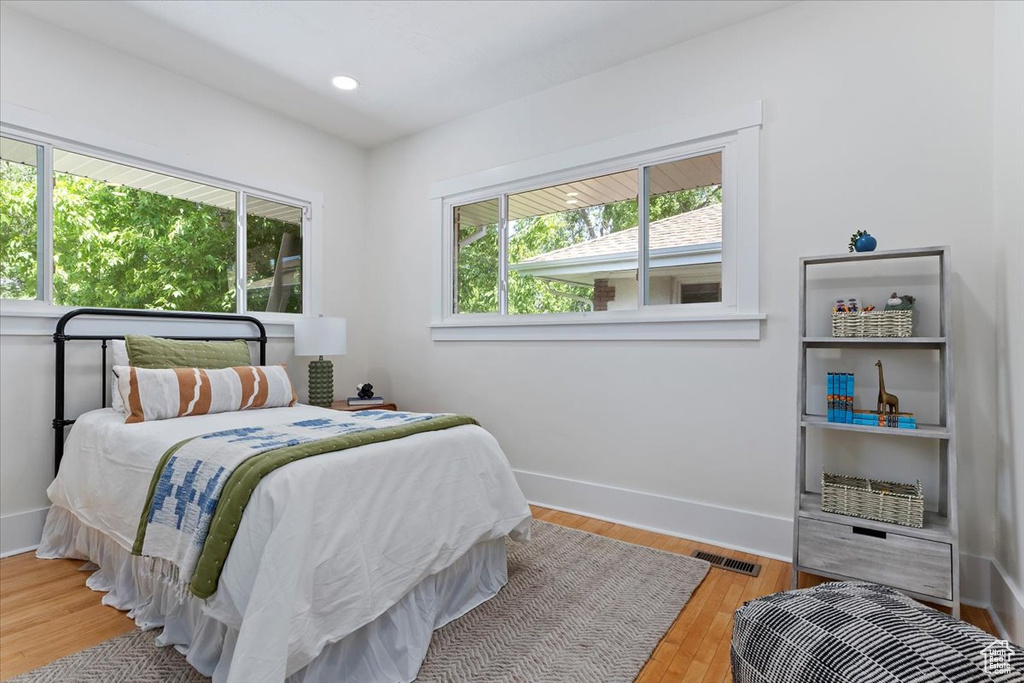 Bedroom featuring multiple windows, wood finished floors, baseboards, and recessed lighting