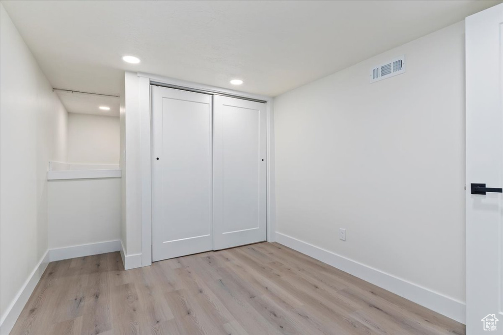 Unfurnished bedroom with baseboards, light wood-style flooring, a closet, and recessed lighting