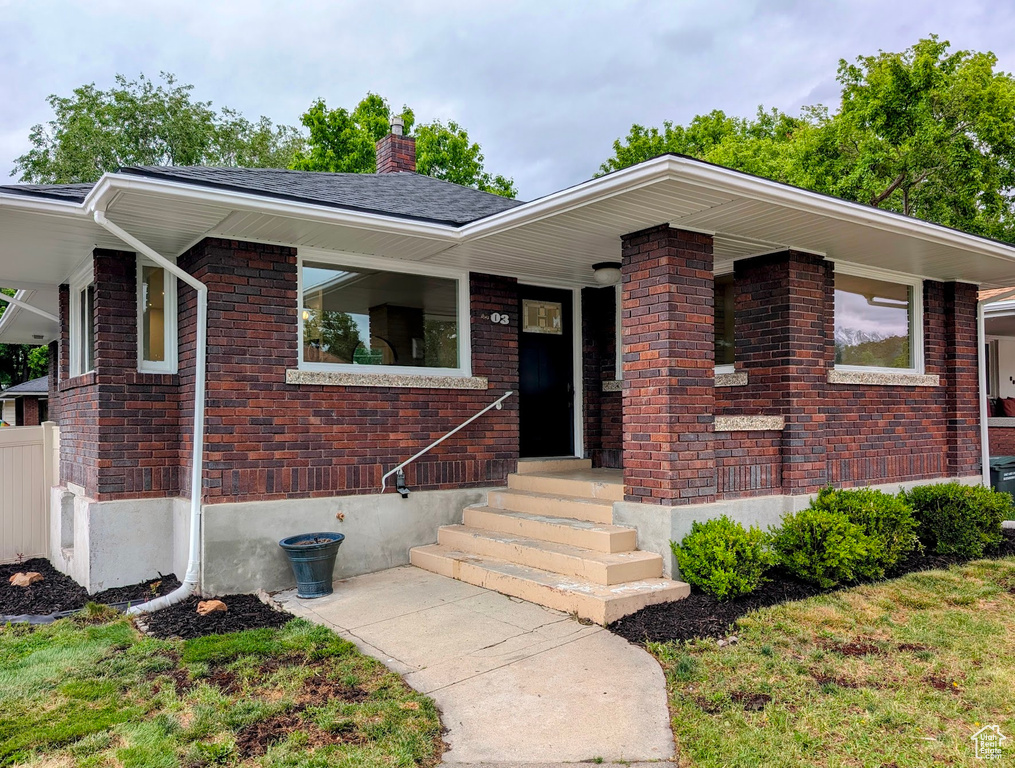 View of front of home with a chimney and brick siding