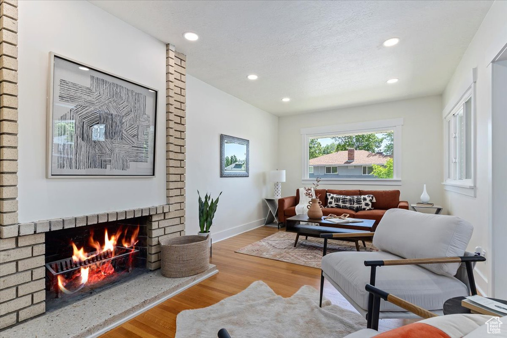 Living area with wood finished floors, a fireplace, recessed lighting, and baseboards