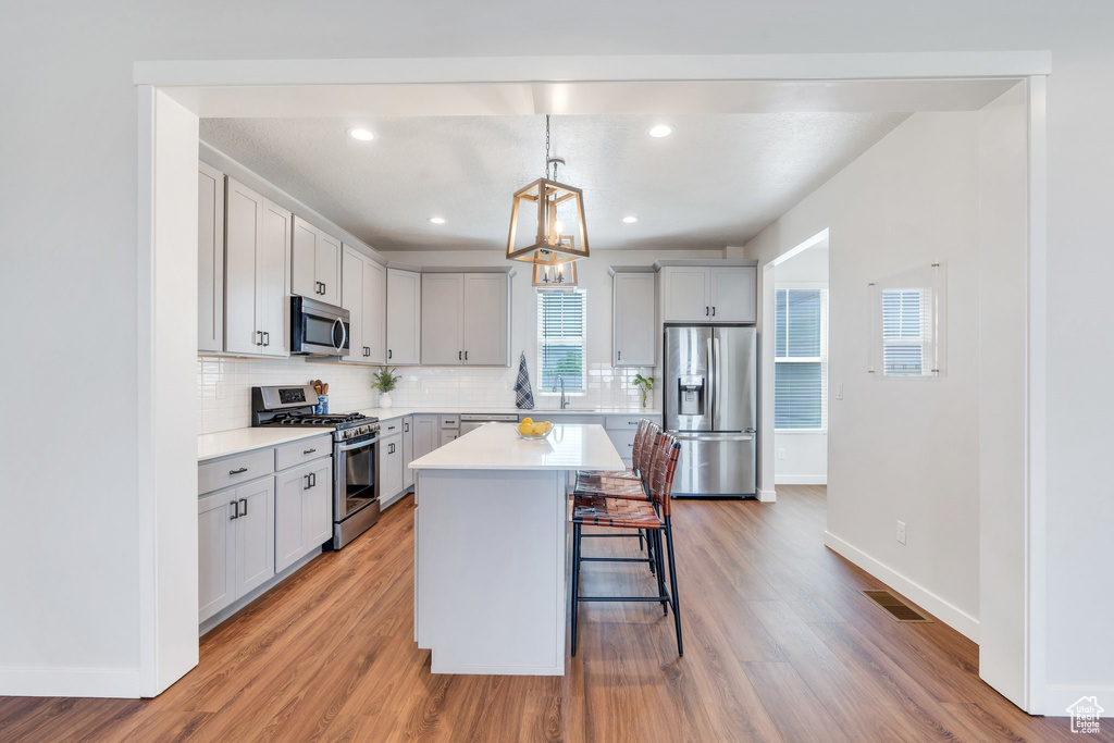 Kitchen with stainless steel appliances, a breakfast bar area, baseboards, decorative backsplash, and recessed lighting