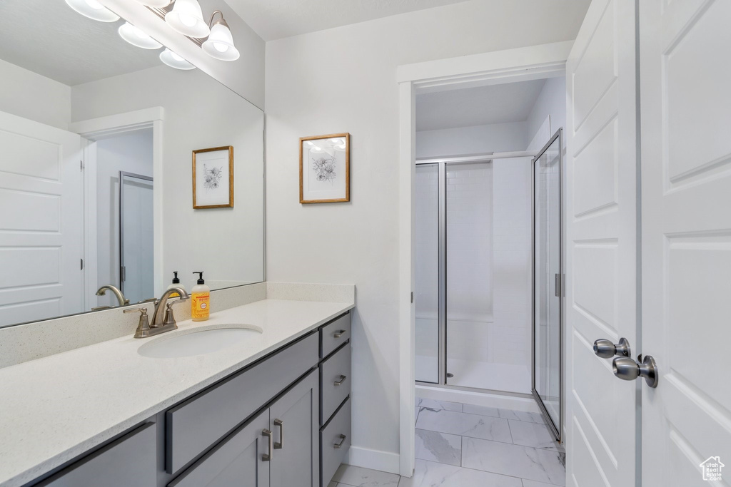 Full bathroom featuring marble finish flooring, a stall shower, baseboards, and vanity