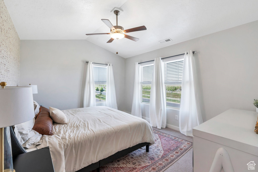 Bedroom with light colored carpet, lofted ceiling, a ceiling fan, and baseboards