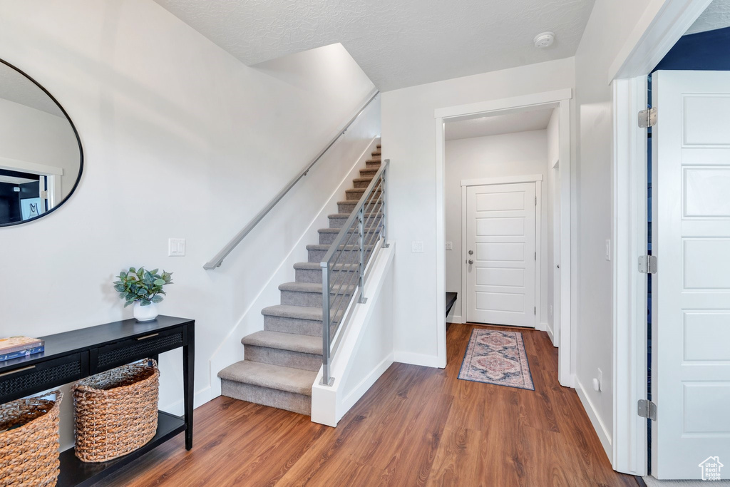 Entryway with wood finished floors, stairs, and baseboards