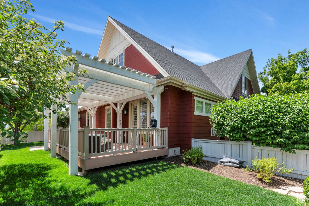 Rear view of property with a pergola, a wooden deck, and roof with shingles