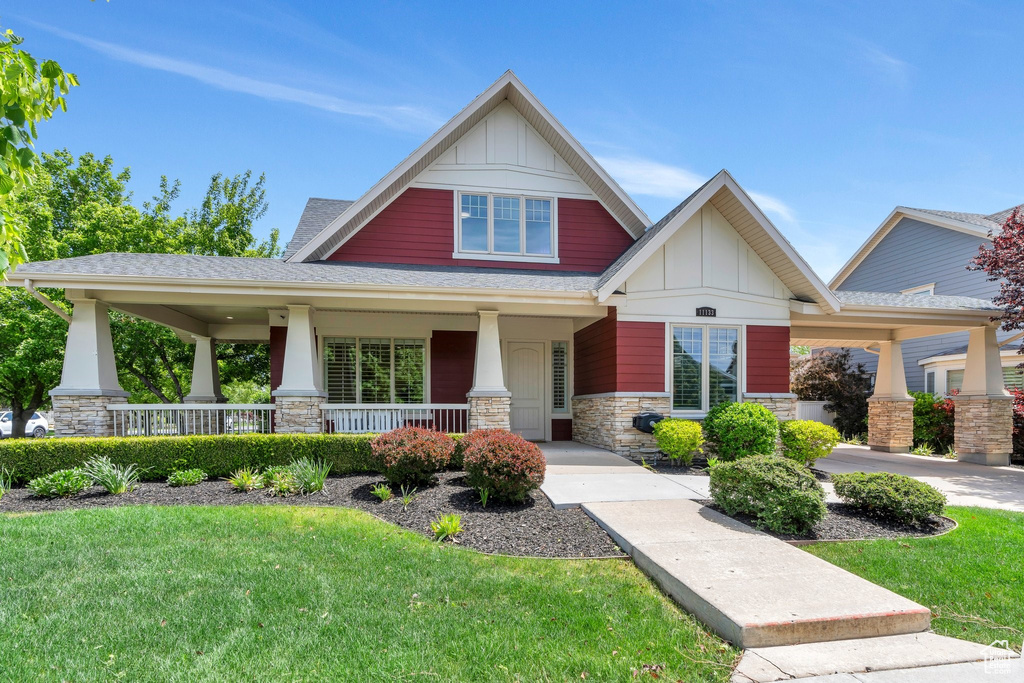 Craftsman-style home featuring board and batten siding, stone siding, a porch, and a front yard