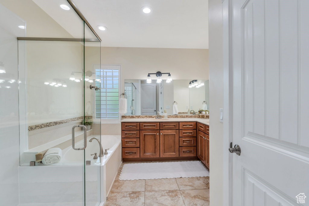 Bathroom with a bath, a shower stall, double vanity, and tile patterned floors