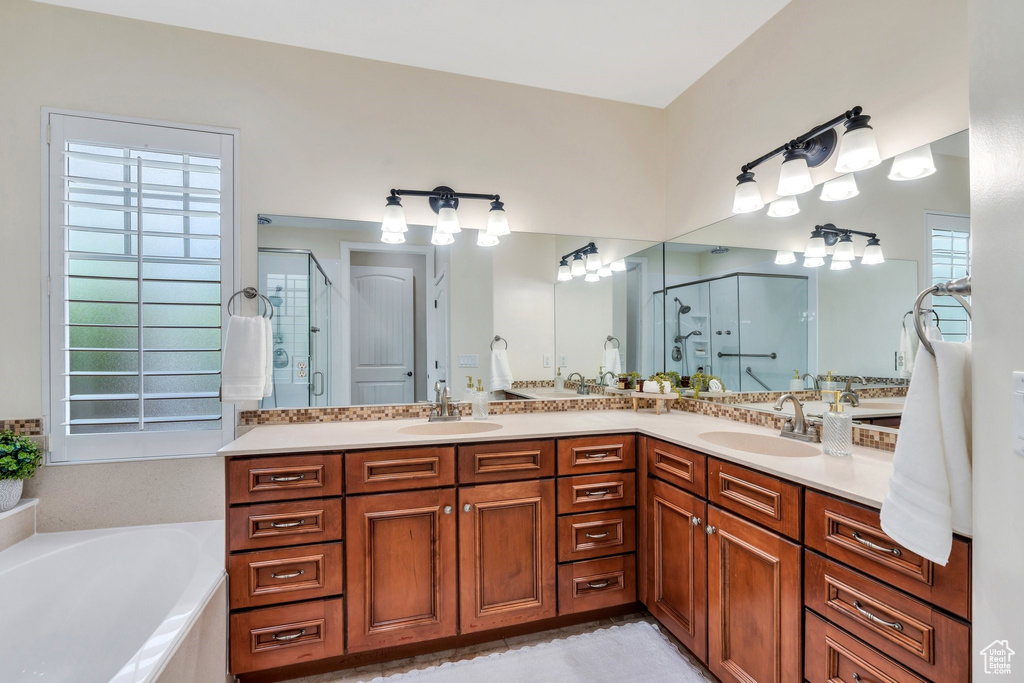 Full bathroom featuring a shower stall, healthy amount of natural light, double vanity, and a garden tub