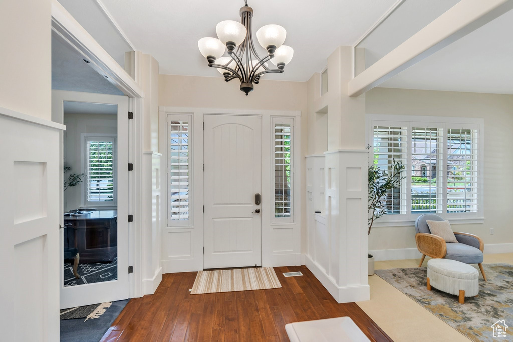 Foyer entrance with dark wood-style flooring and a chandelier