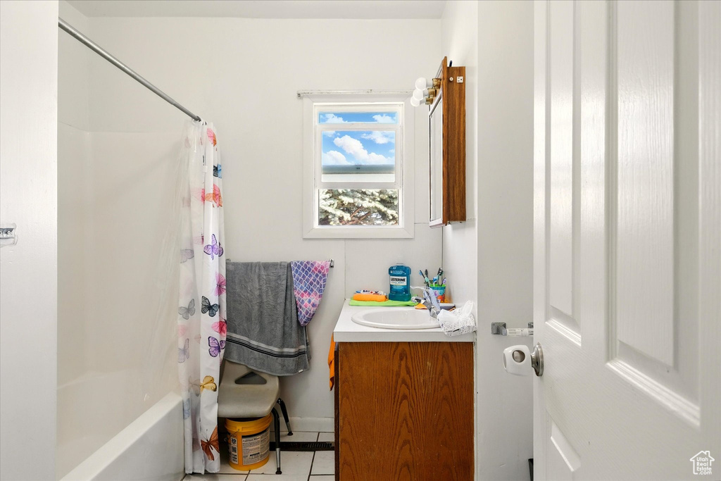 Bathroom with vanity, tile patterned flooring, shower / bathtub combination with curtain, and baseboards