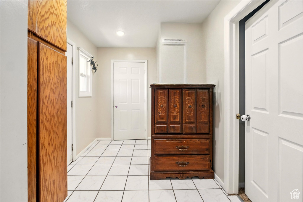 Hall with light tile patterned flooring and baseboards