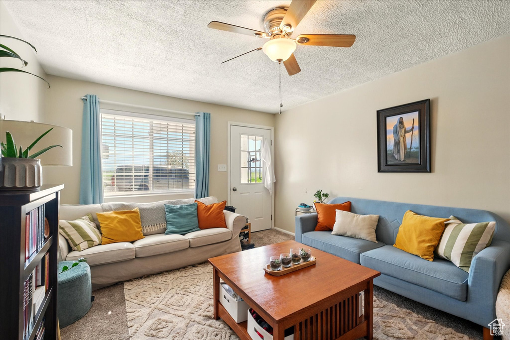 Living room with a ceiling fan, a textured ceiling, and light colored carpet