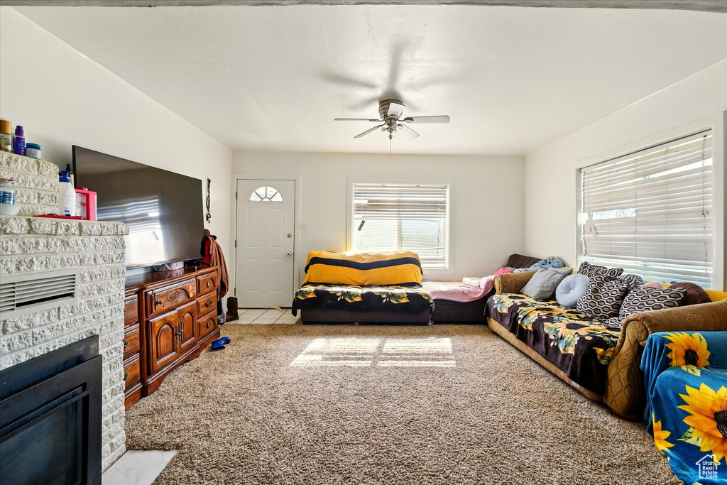 Carpeted living area with a ceiling fan and a glass covered fireplace