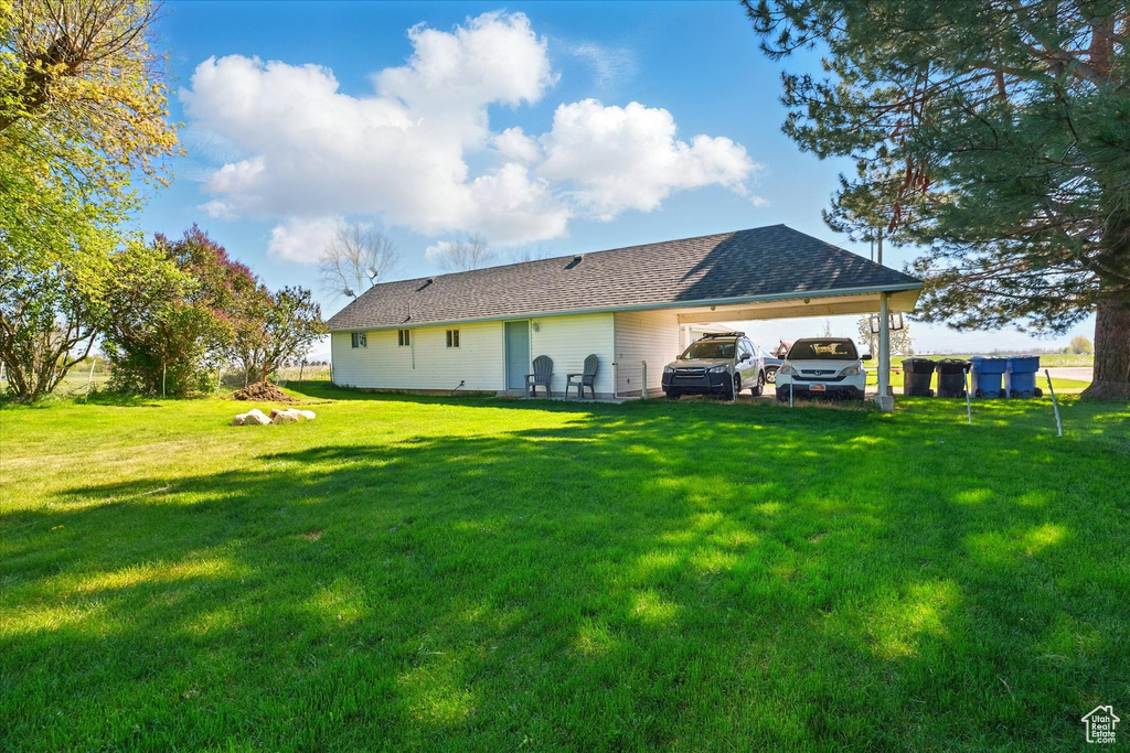 Rear view of property featuring a lawn and a carport