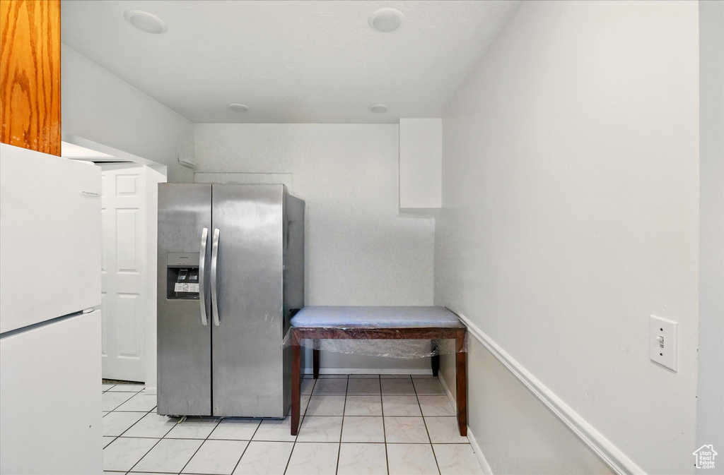 Kitchen featuring stainless steel fridge, freestanding refrigerator, and light tile patterned floors