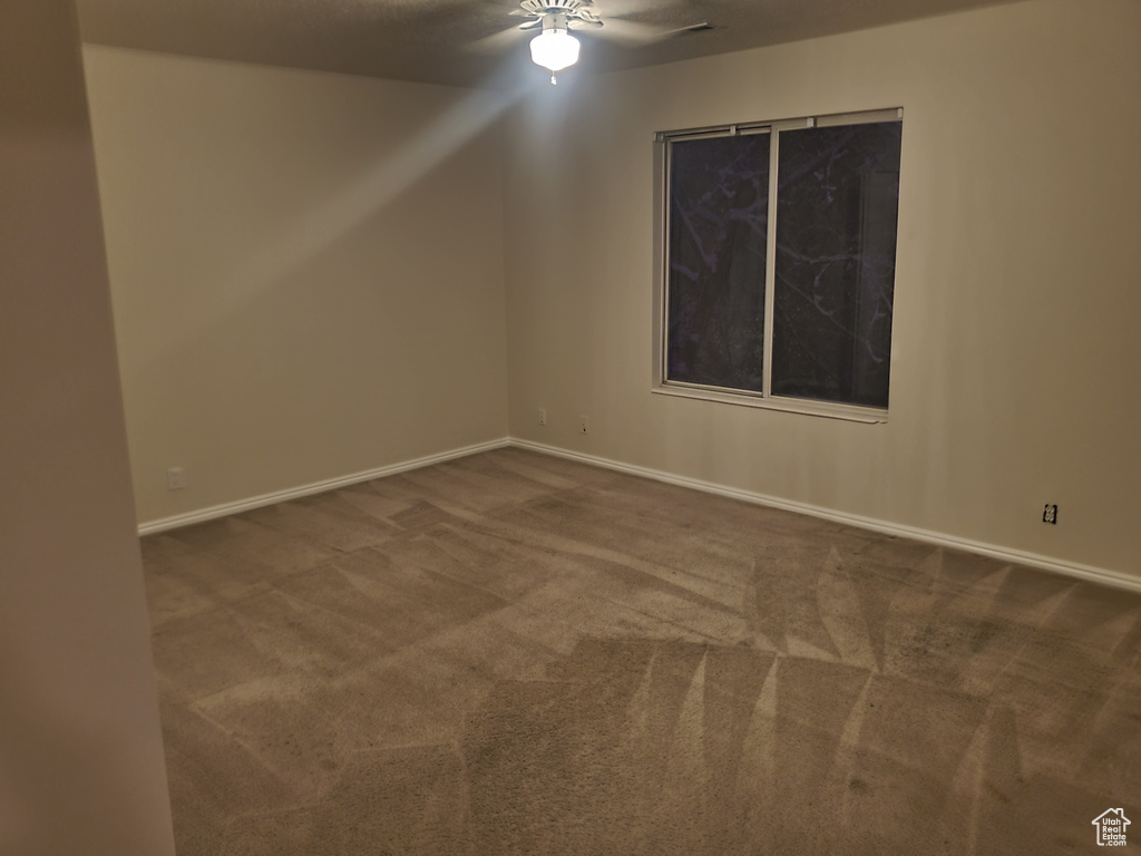 Carpeted empty room with a ceiling fan and baseboards