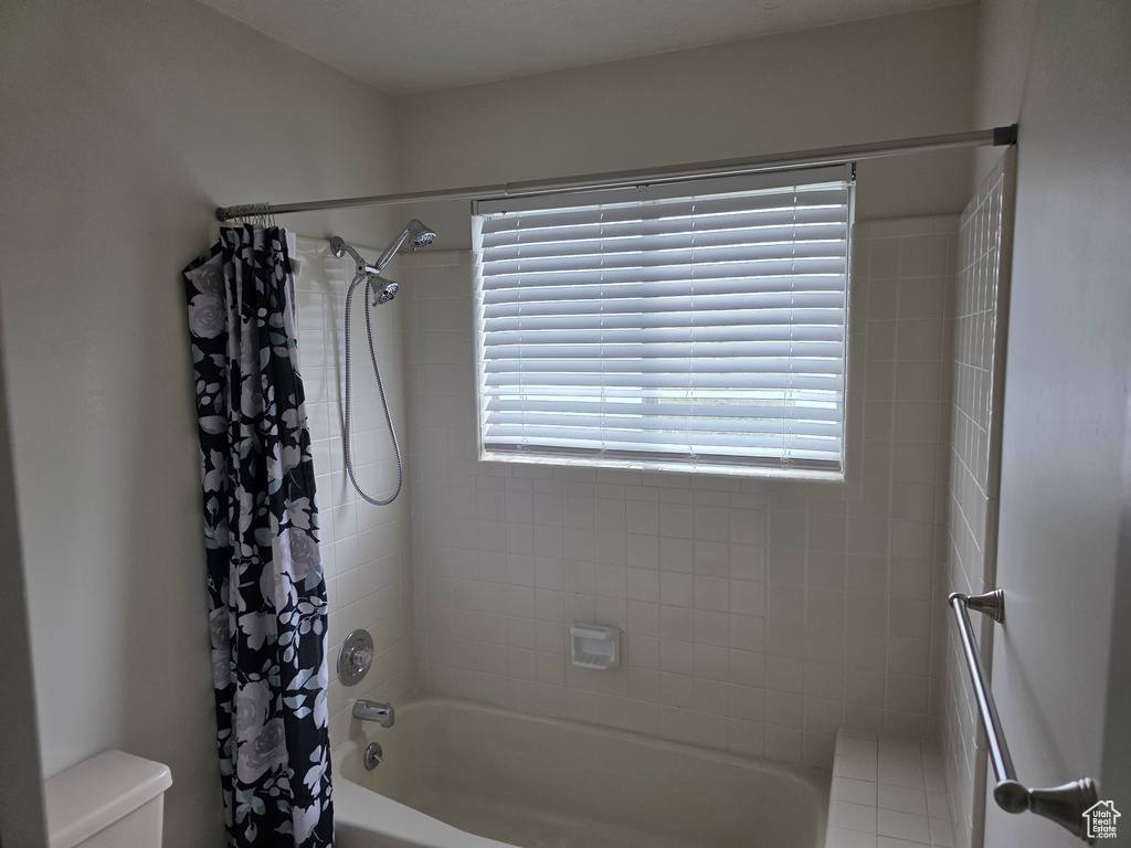 Full bathroom with toilet, plenty of natural light, and shower / bath combo with shower curtain