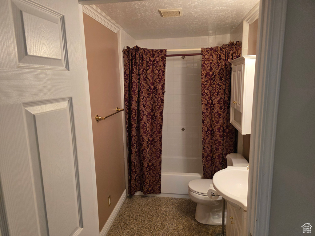 Bathroom featuring a textured ceiling, toilet, vanity, shower / bath combo with shower curtain, and baseboards