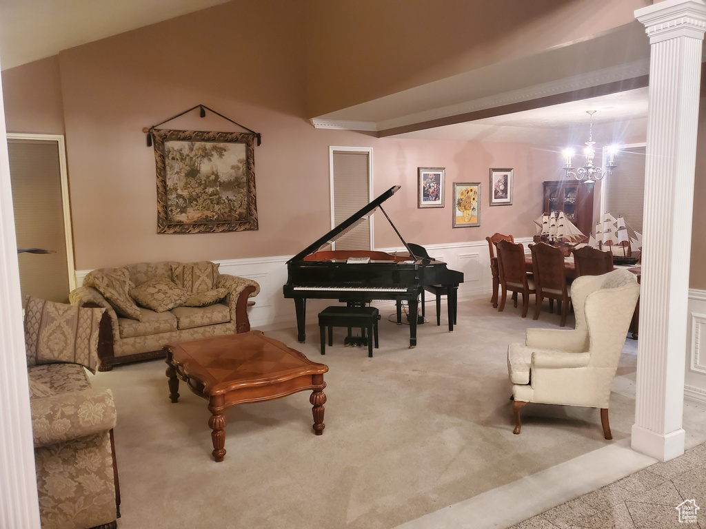 Living room with carpet flooring, a chandelier, decorative columns, wainscoting, and a decorative wall