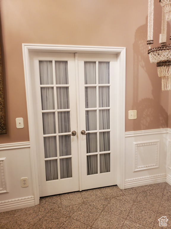 Doorway to outside featuring granite floors, wainscoting, french doors, and a decorative wall