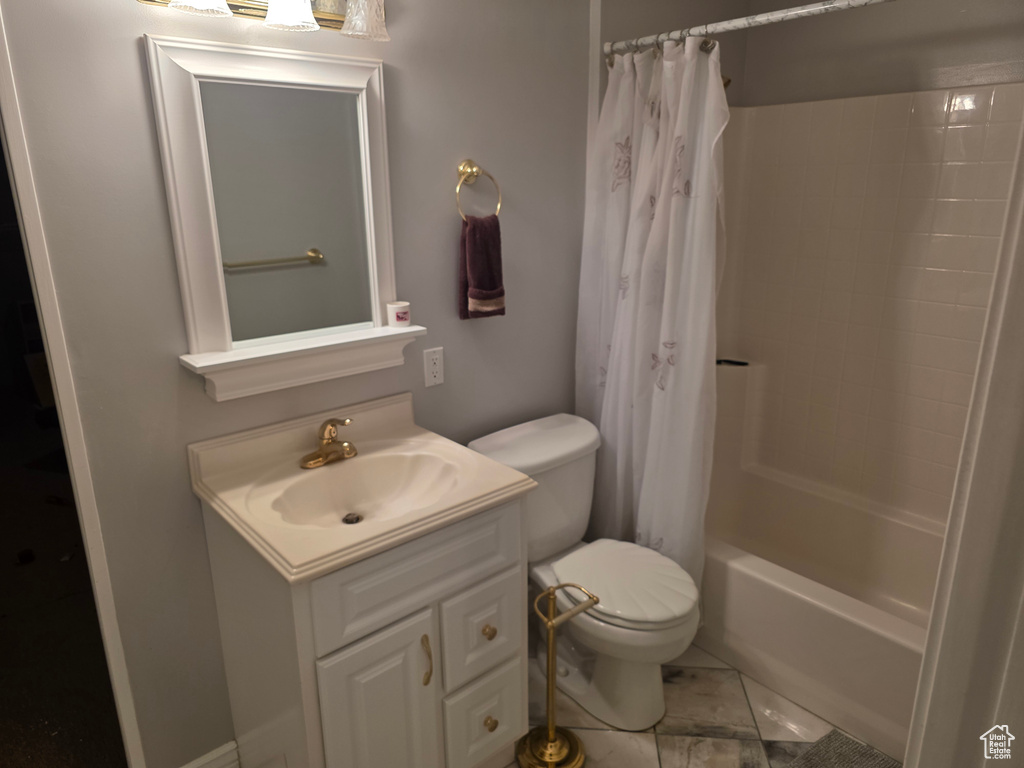 Full bath featuring toilet, vanity, shower / bathtub combination with curtain, and marble look tiles