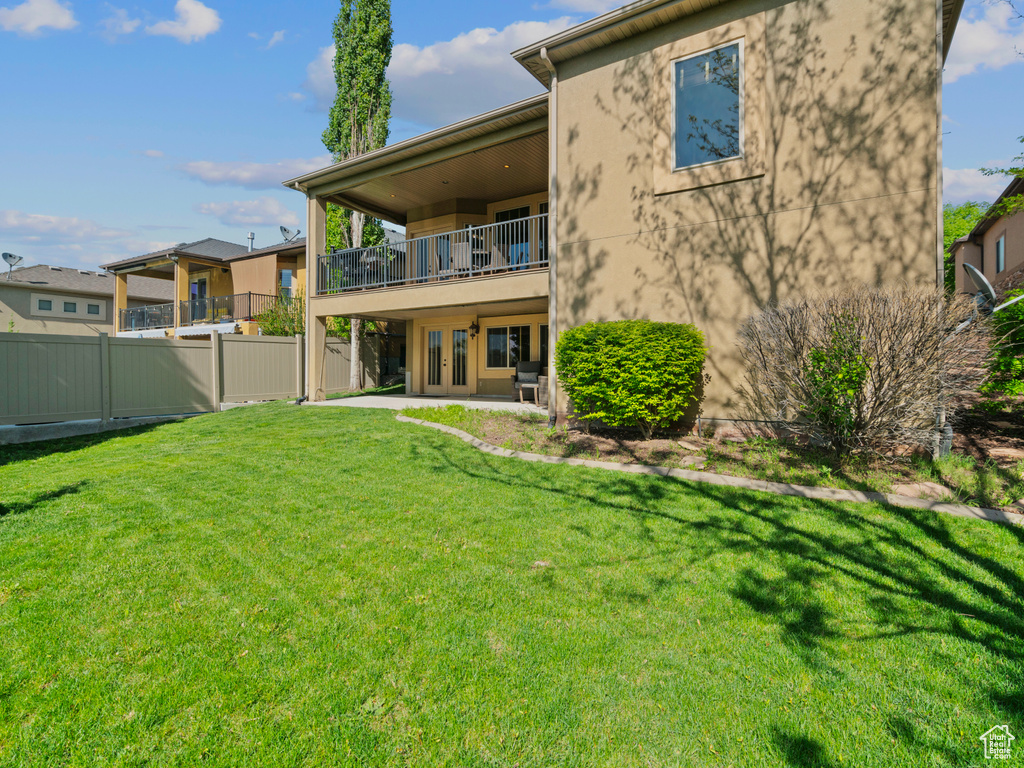 Rear view of house featuring a balcony, french doors, a patio area, and stucco siding