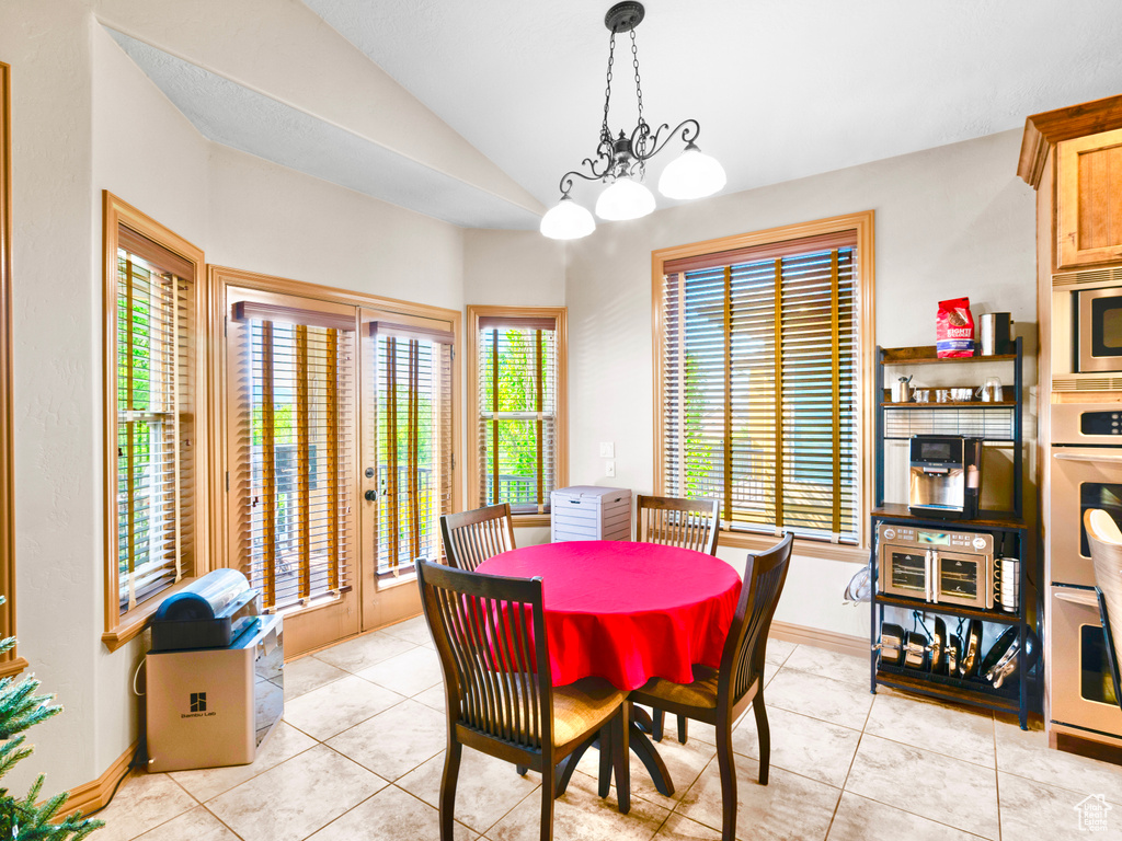 Dining space with lofted ceiling, light tile patterned flooring, and baseboards