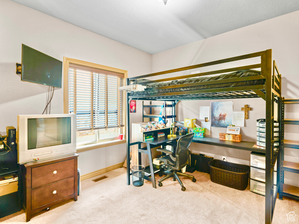 Carpeted bedroom with an office area and baseboards