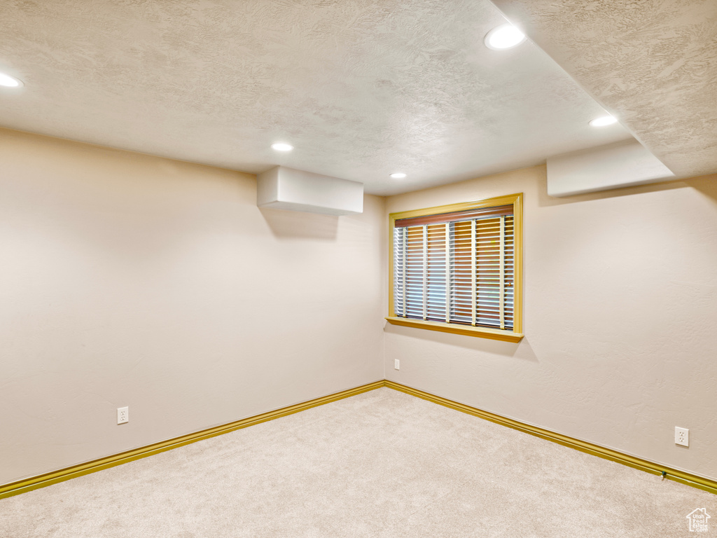 Finished below grade area with recessed lighting, carpet flooring, baseboards, and a textured ceiling