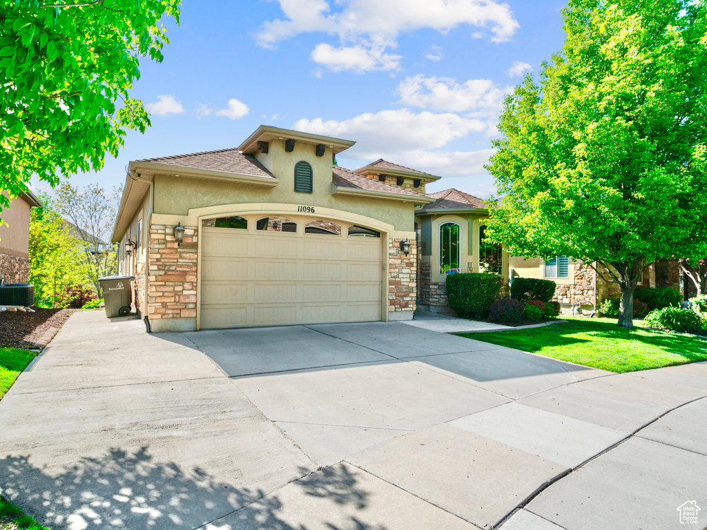 Mediterranean / spanish home with stucco siding, stone siding, driveway, and a garage