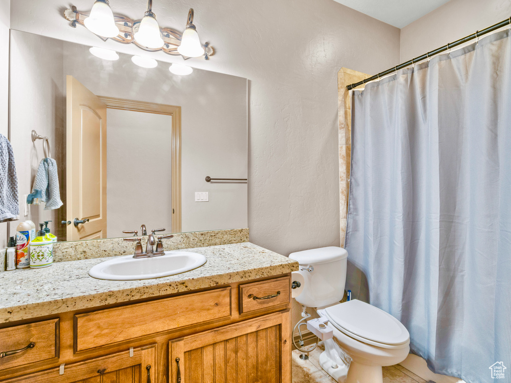 Full bathroom featuring toilet, vanity, and curtained shower