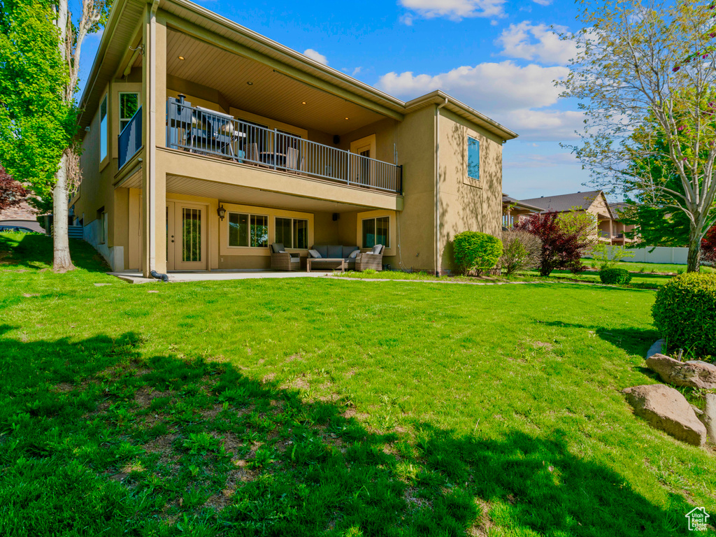 Rear view of property with a balcony, stucco siding, outdoor lounge area, and a yard