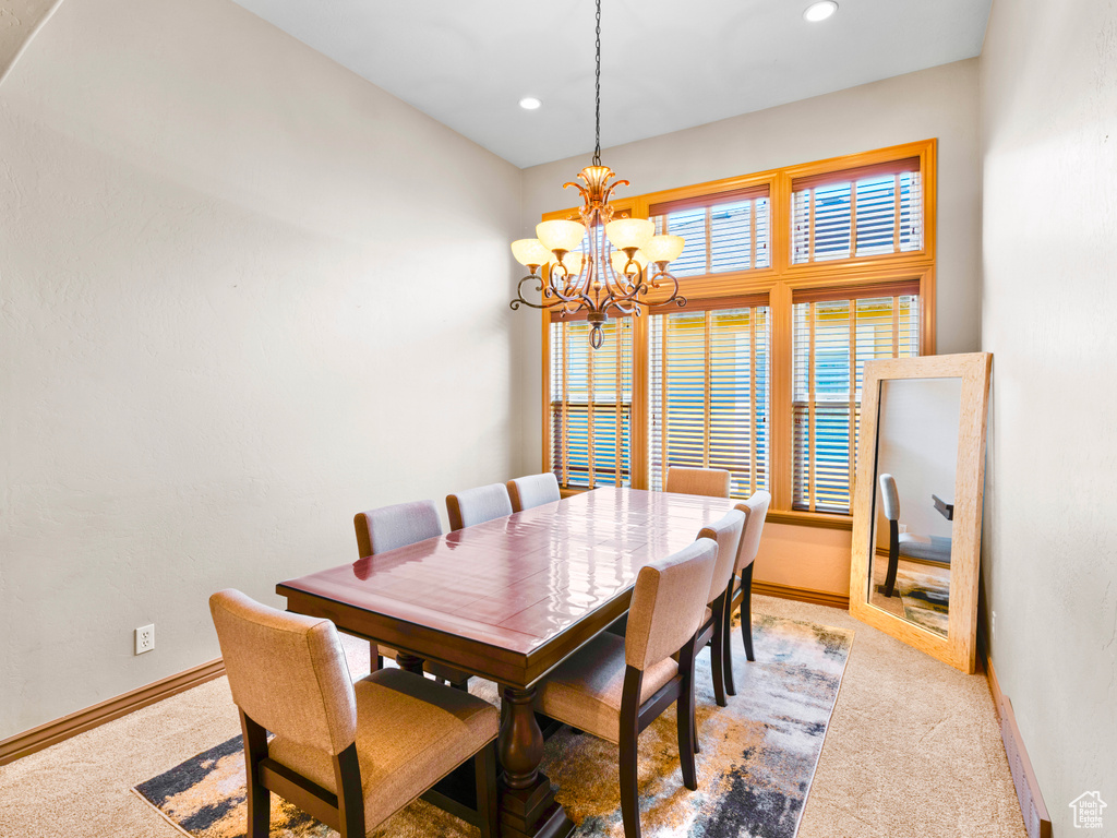 Dining area with light colored carpet, a chandelier, baseboards, and recessed lighting