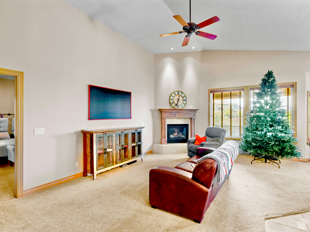 Living area with carpet floors, a ceiling fan, a fireplace, high vaulted ceiling, and baseboards