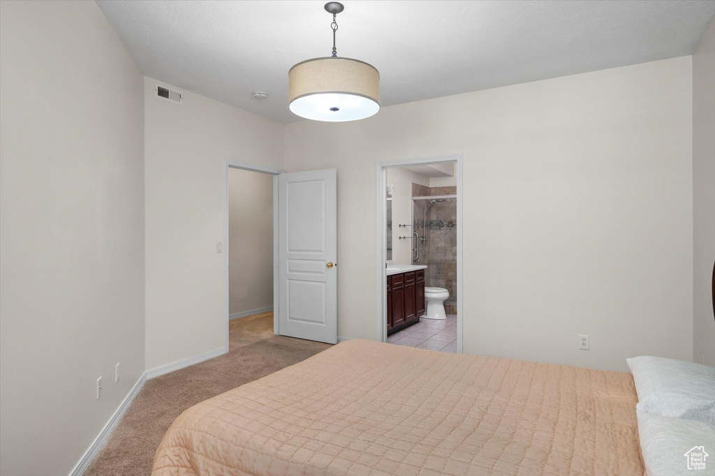 Bedroom featuring light carpet, baseboards, and ensuite bathroom