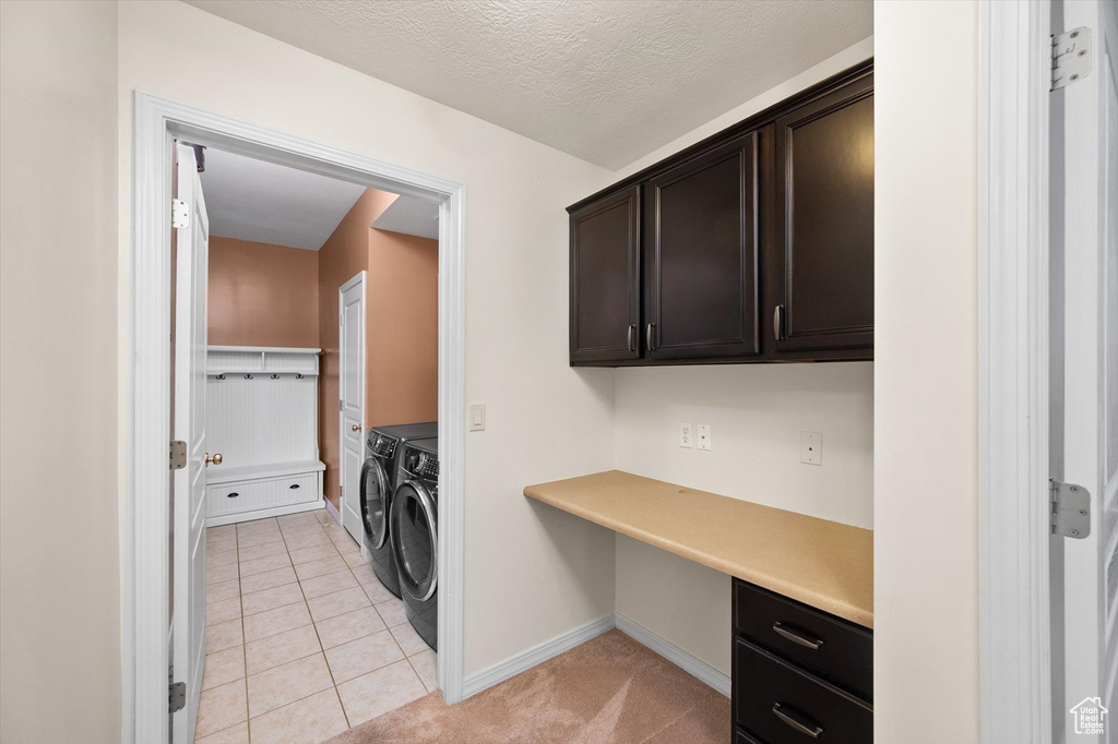 Washroom with washing machine and dryer, a desk, baseboards, cabinet space, and light tile patterned flooring