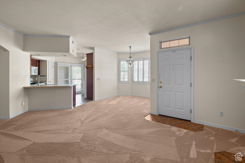 Foyer entrance featuring carpet, ornamental molding, a chandelier, and baseboards