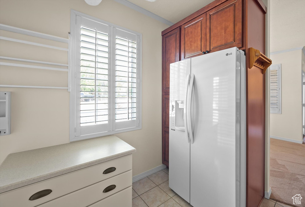 Kitchen featuring white fridge with ice dispenser, plenty of natural light, light countertops, and light tile patterned flooring