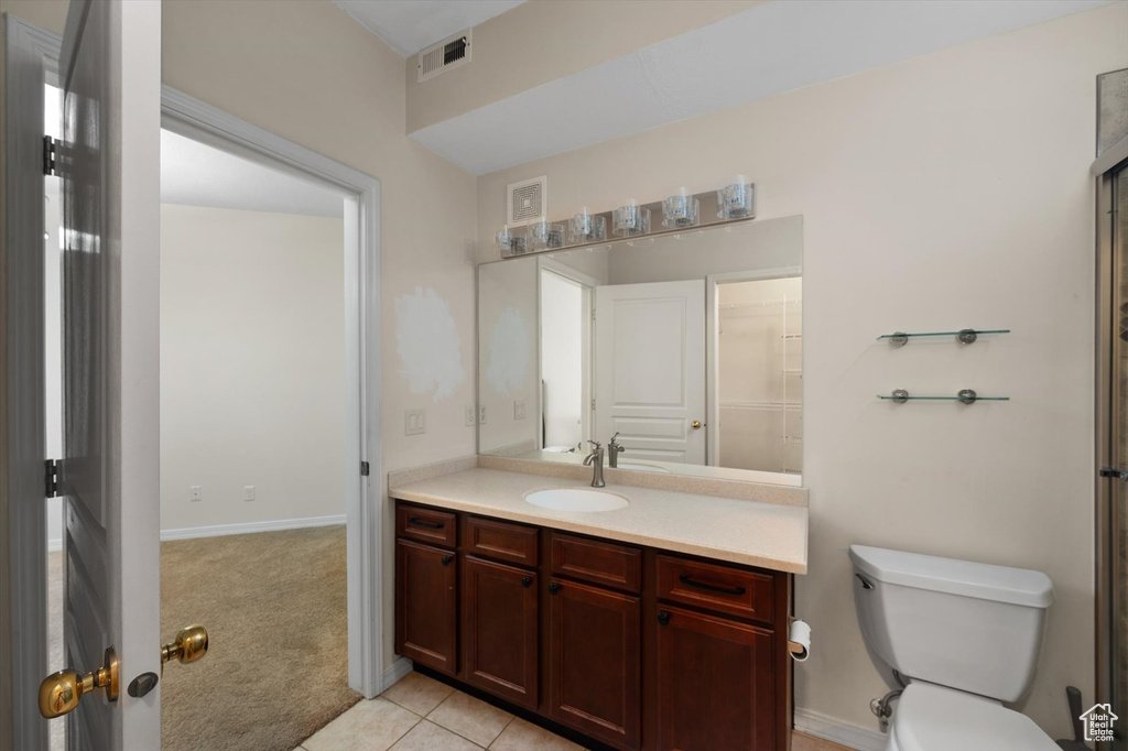 Bathroom with toilet, vanity, tile patterned flooring, and baseboards