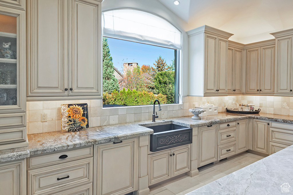 Kitchen with a sink, cream cabinetry, tasteful backsplash, and healthy amount of natural light