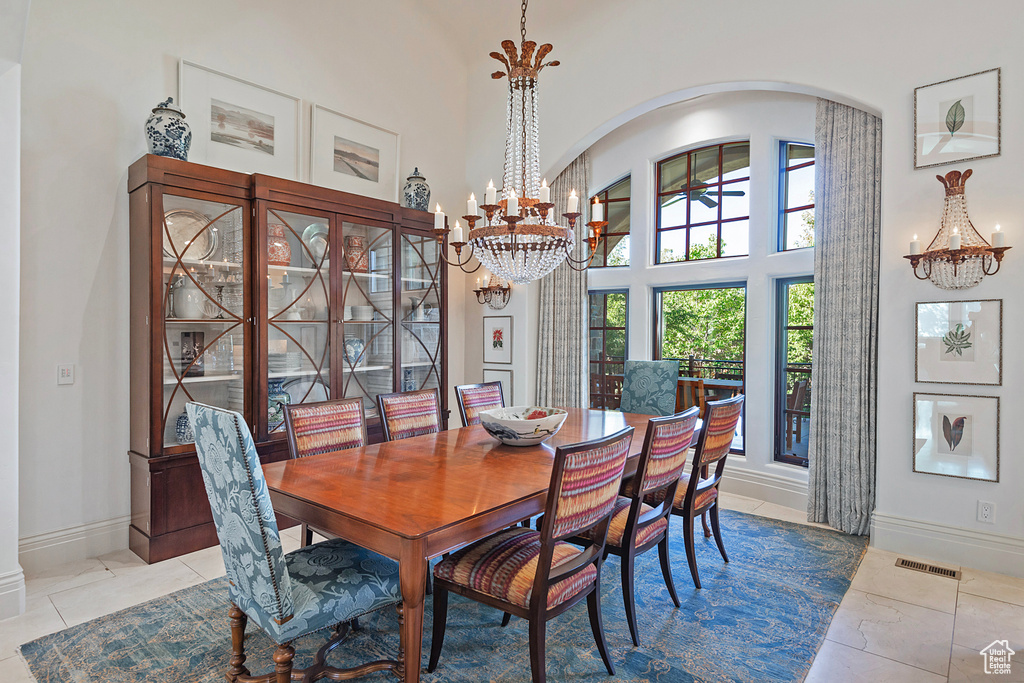 Tiled dining space featuring a chandelier, arched walkways, baseboards, and a high ceiling