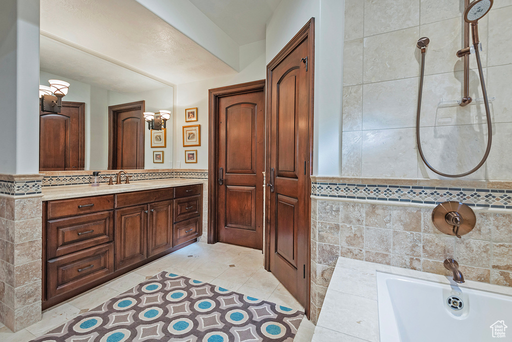 Full bath featuring a bath, vanity, tile walls, and tile patterned floors