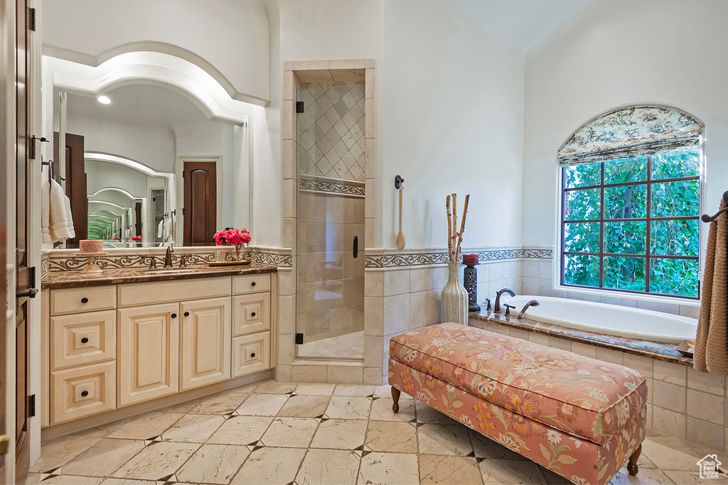 Full bath featuring a stall shower, vanity, a garden tub, and tile patterned flooring