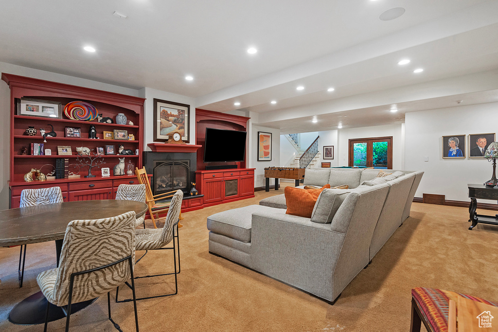 Living area featuring light carpet, a glass covered fireplace, recessed lighting, and stairs