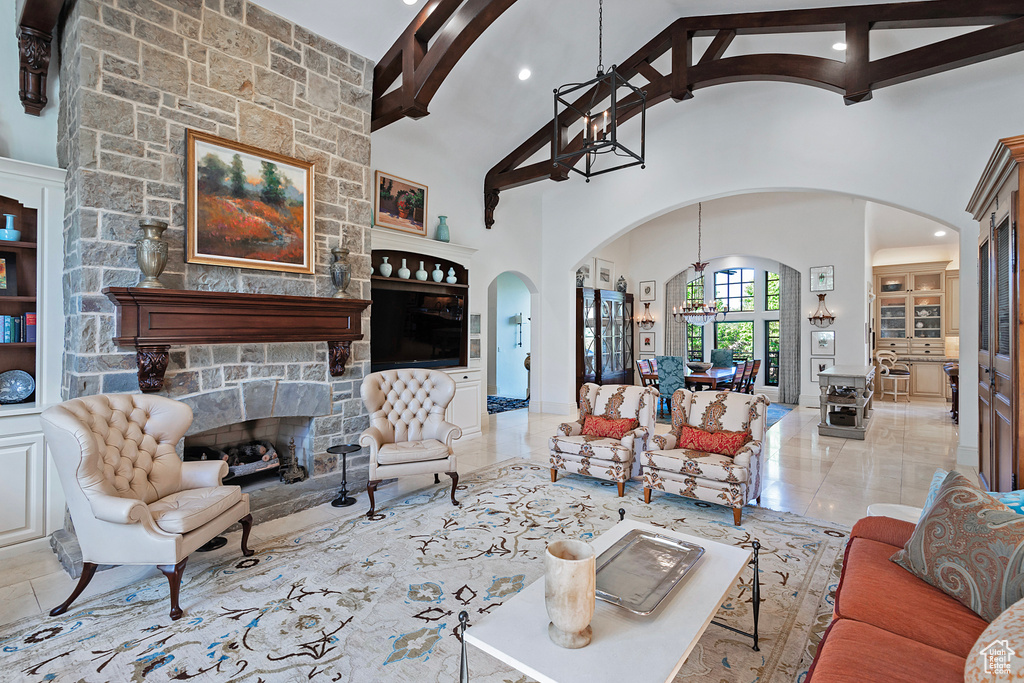 Living area with arched walkways, beamed ceiling, high vaulted ceiling, a fireplace, and recessed lighting